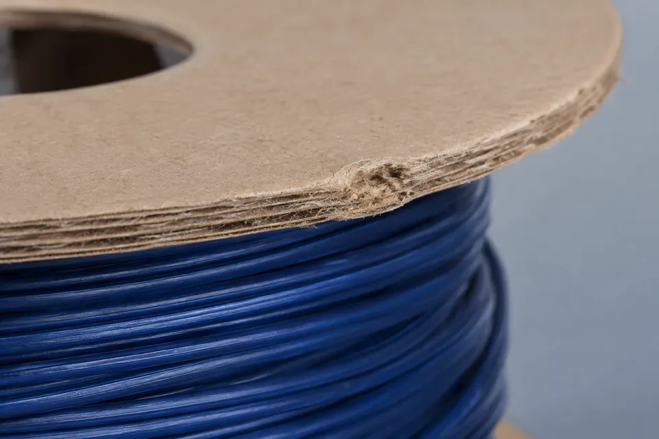 Close view of a rough, locally dented cardboard spool rim.